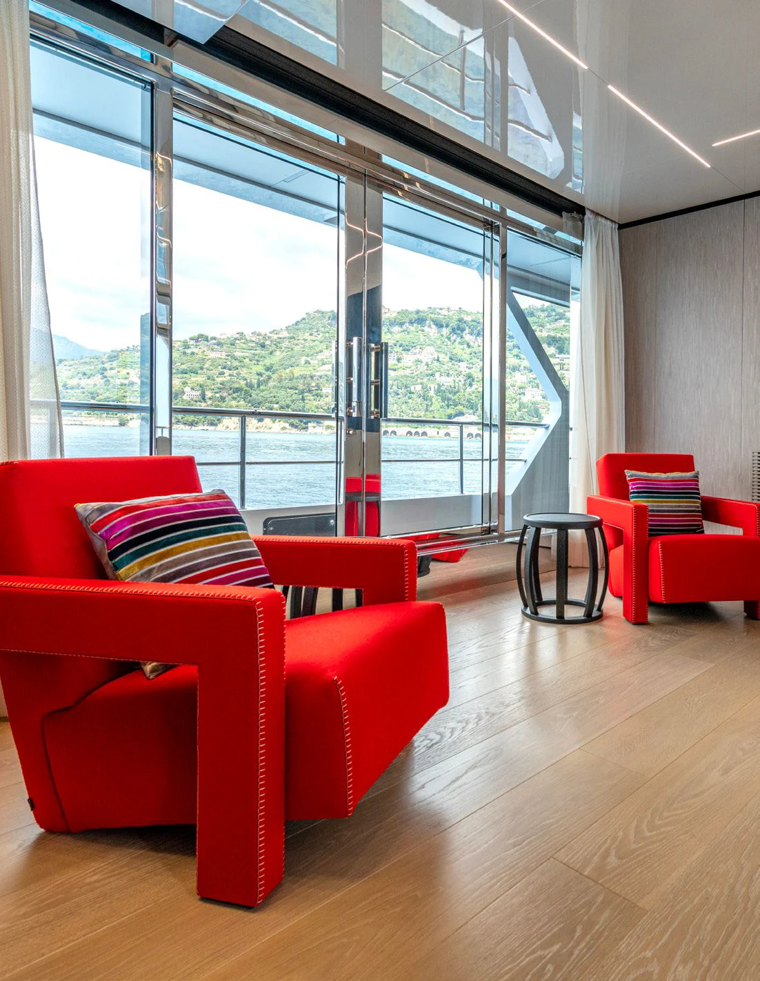 a room with red chairs and a large window aboard CARITA Yacht for Sale