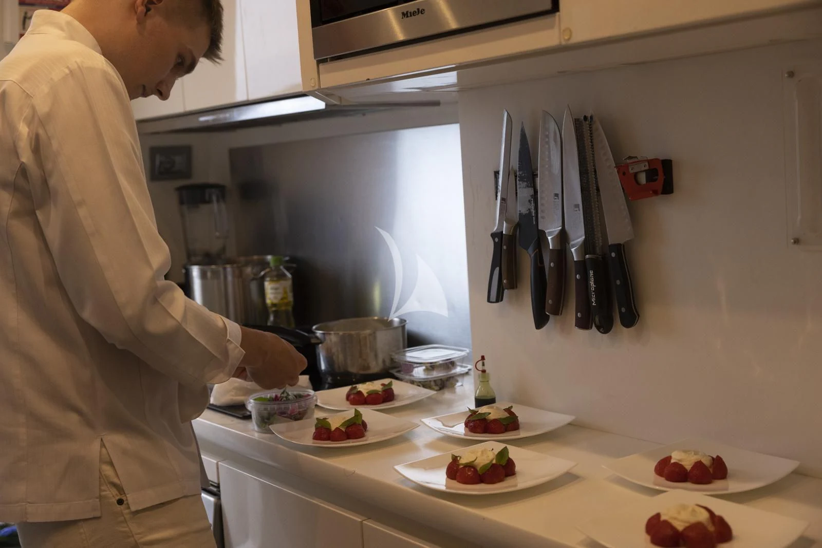 a man is preparing food in a kitchen aboard XUMI Yacht for Charter