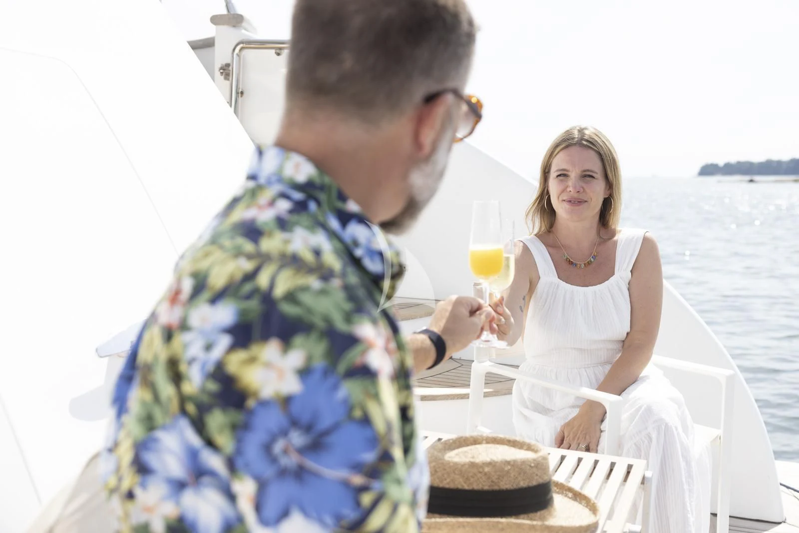 a man and woman holding glasses of champagne and a cake on a boat aboard XUMI Yacht for Charter