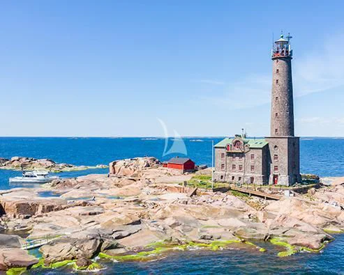 a lighthouse on a rocky beach aboard XUMI Yacht for Charter