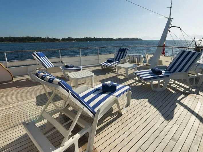 a deck with lounge chairs and a body of water in the background aboard FIVE ANGELS Yacht for Sale