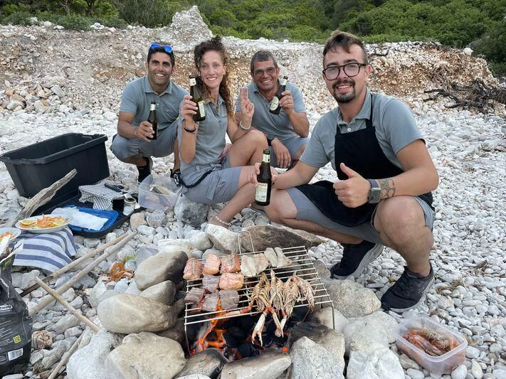 a group of people sitting on a pile of food and drinking beer aboard MIAMAA Yacht for Sale