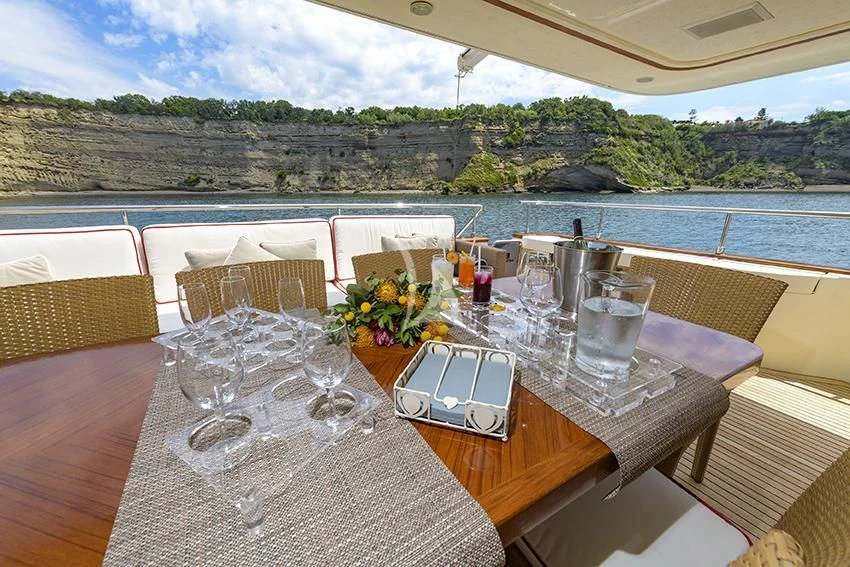 a table with wine glasses and a view of a lake aboard ANNE MARIE Yacht for Sale
