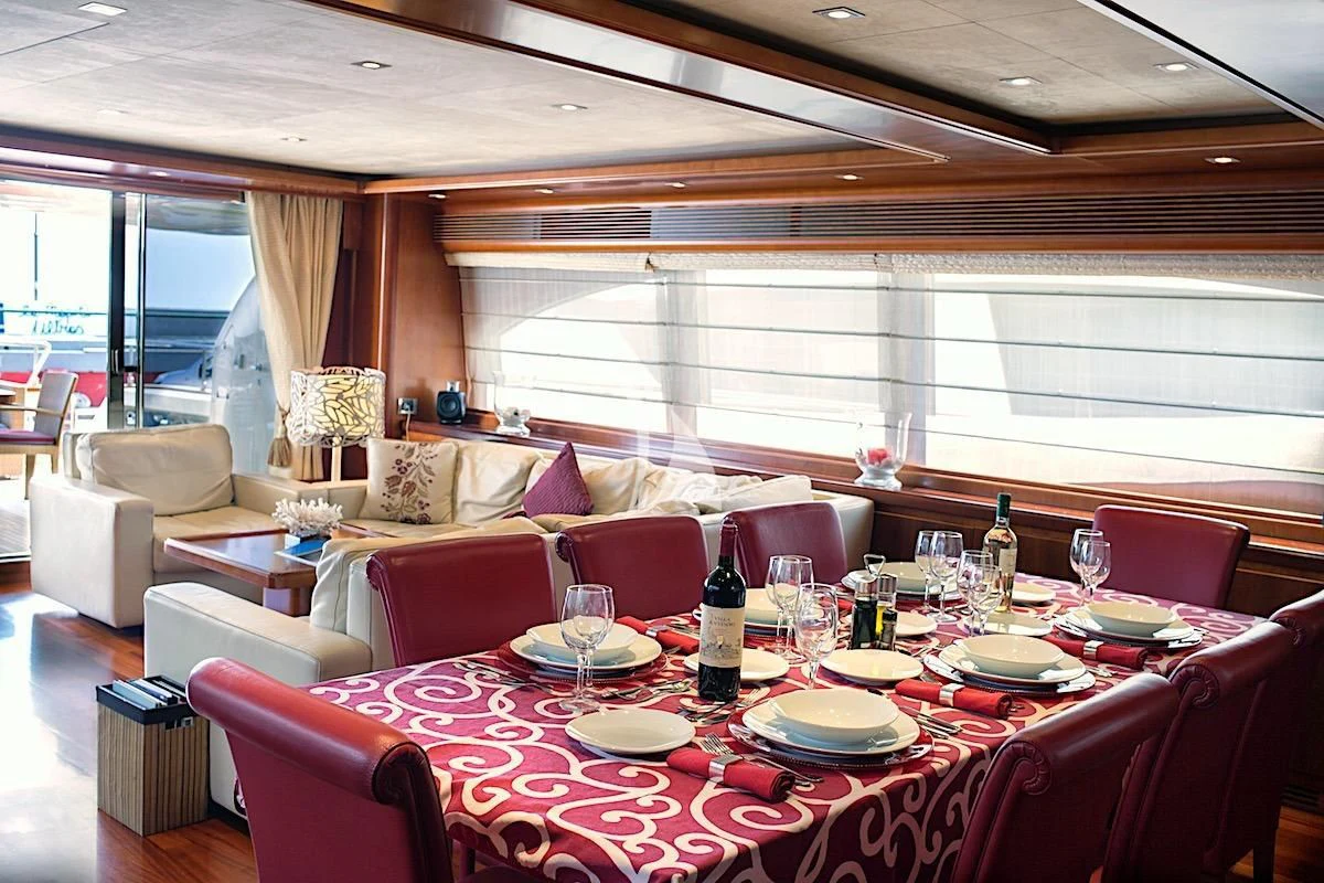 a dining table with a wine bottle and a large window aboard ANNE MARIE Yacht for Sale