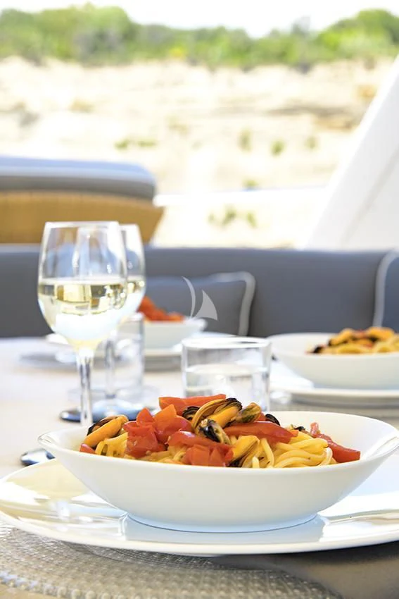 a plate of food and a glass of wine on a table aboard ANNE MARIE Yacht for Sale