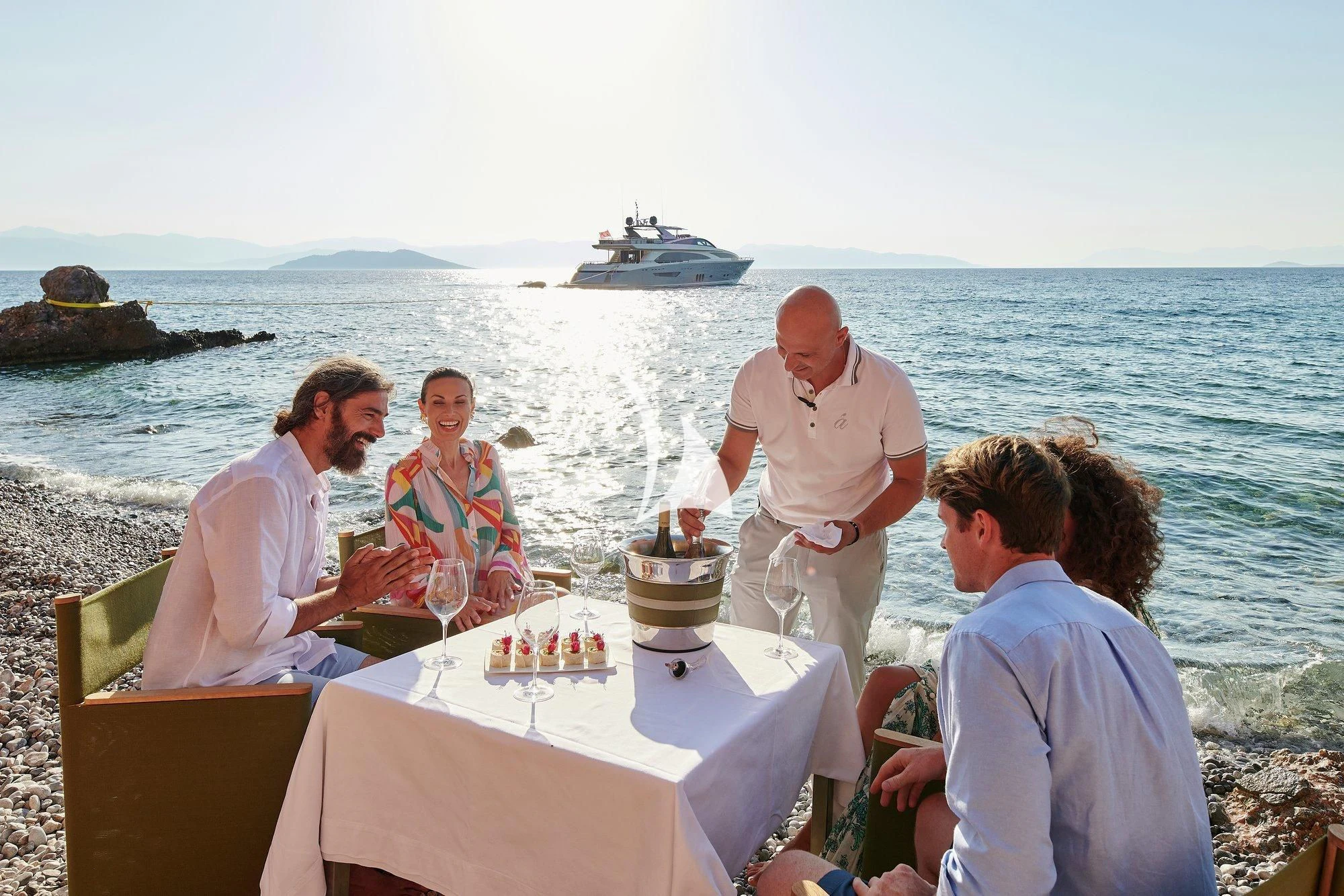 a group of people sitting at a table with food and drinks on it aboard APMONIA Yacht for Sale