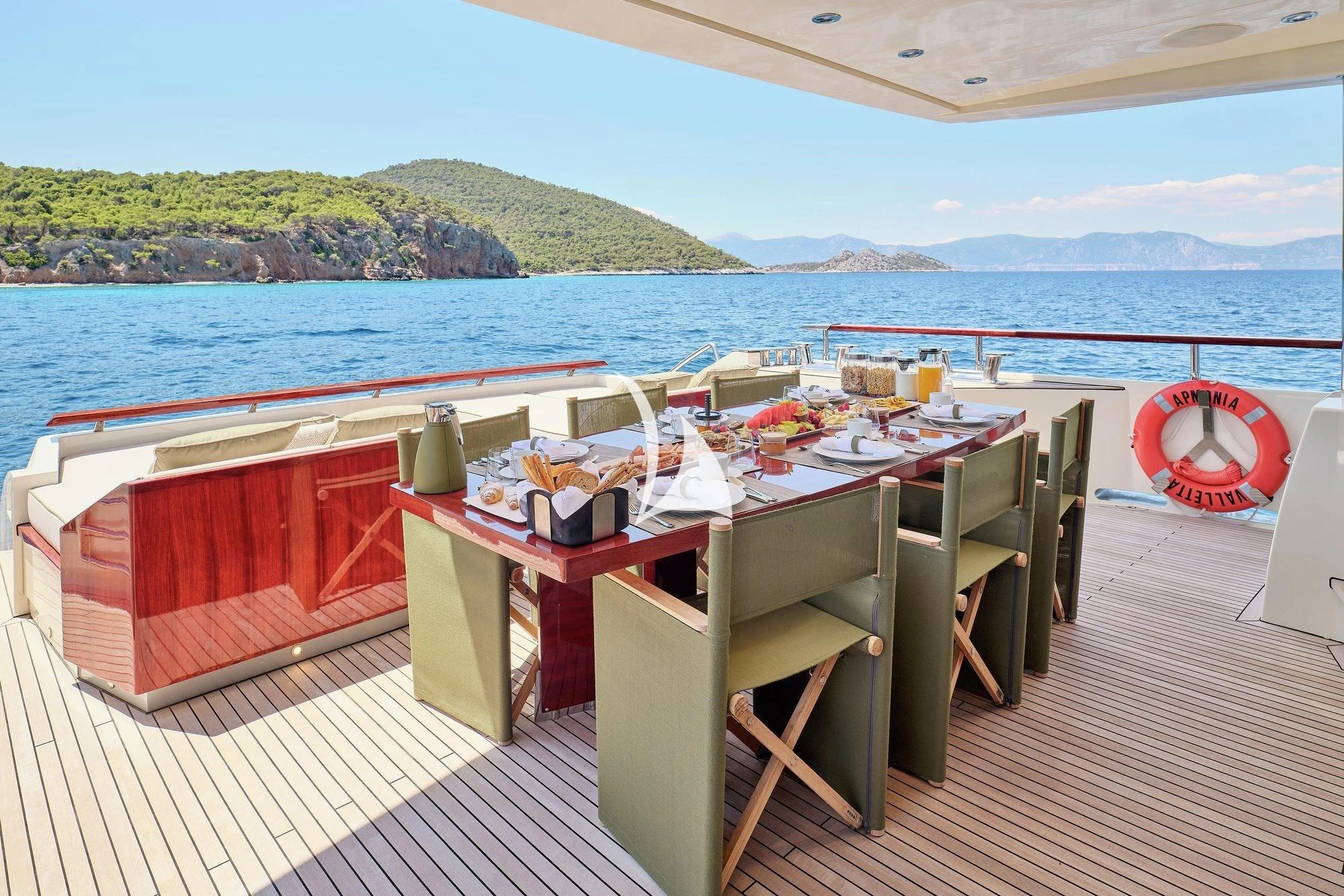 a deck with tables and chairs on it next to a body of water aboard APMONIA Yacht for Sale