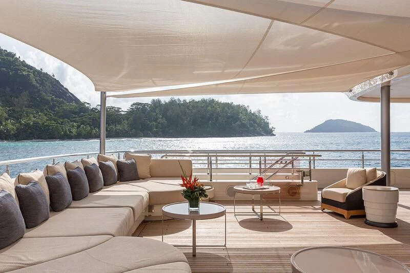 a living room with a large body of water and mountains in the background aboard ROMEA Yacht for Sale