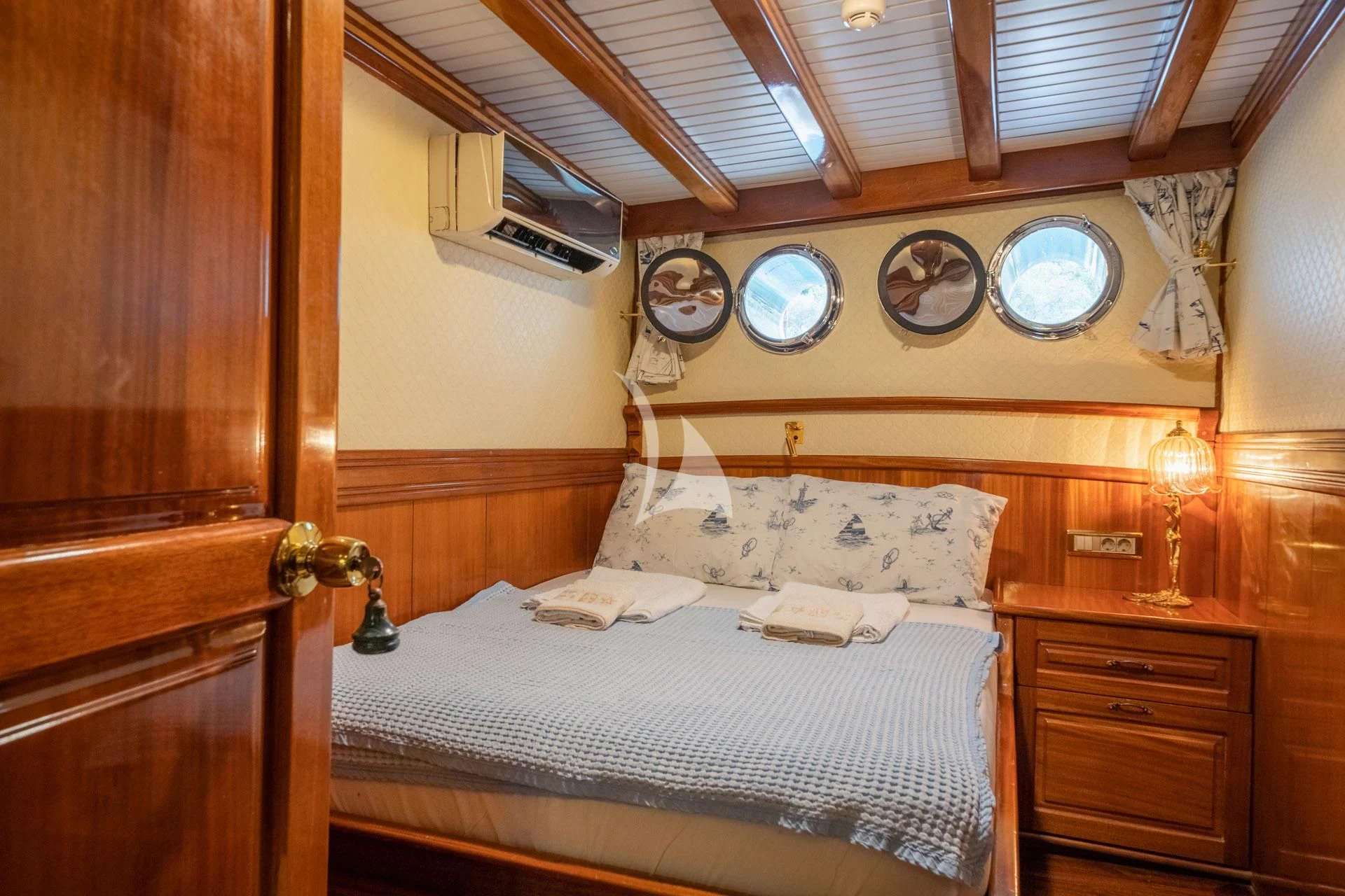 a bed with a white sheet and a clock on the wall aboard ADMIRAL Yacht for Charter