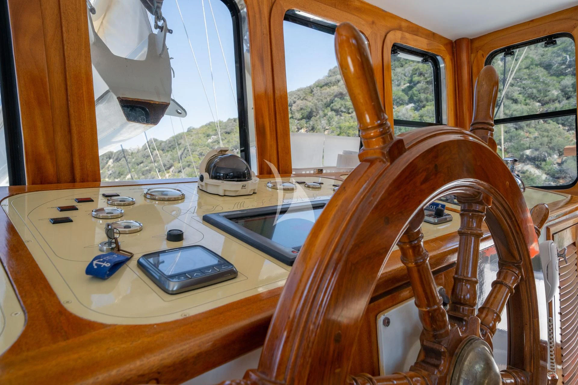 a wooden steering wheel with a phone on it aboard ADMIRAL Yacht for Charter