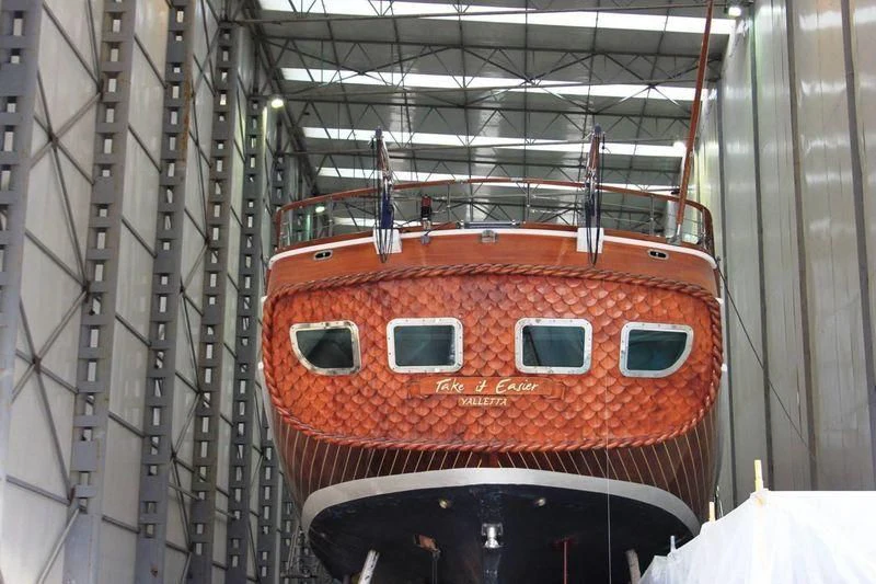 a large orange boat in a large warehouse aboard TAKE IT EASIER Yacht for Sale