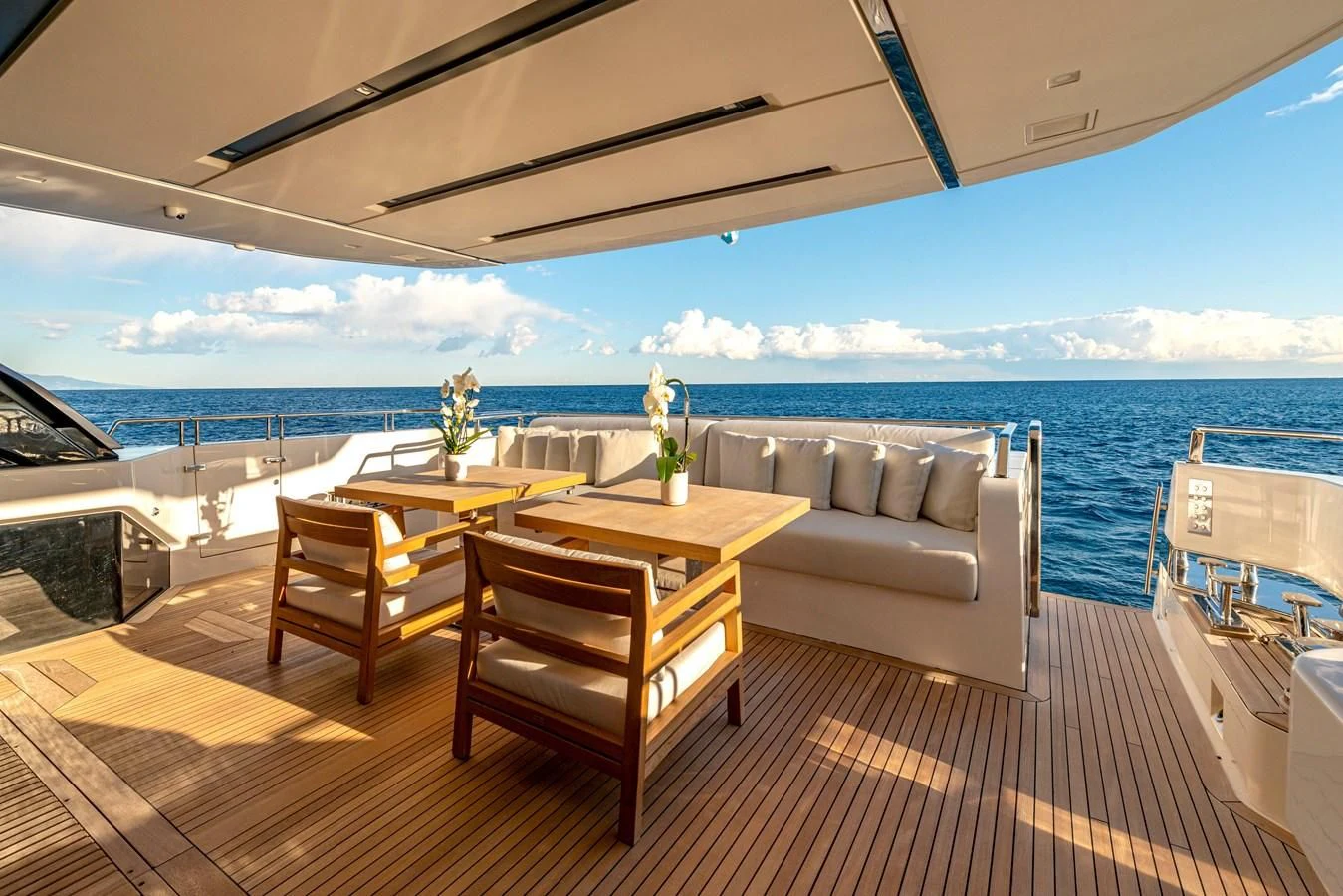a table and chairs on a deck overlooking a large body of water aboard AMWAJ Yacht for Sale