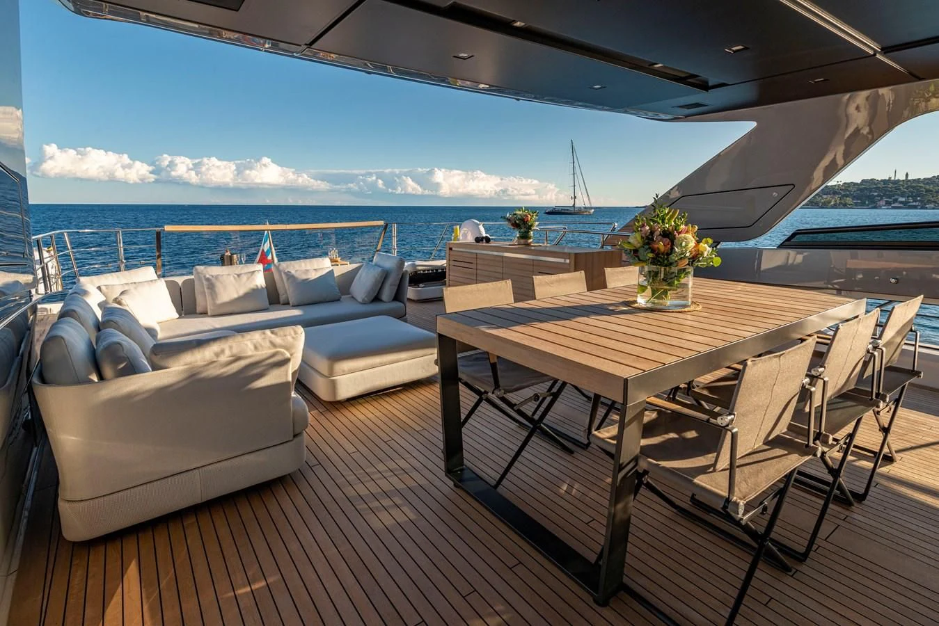 a table and chairs on a deck overlooking a body of water aboard AMWAJ Yacht for Sale