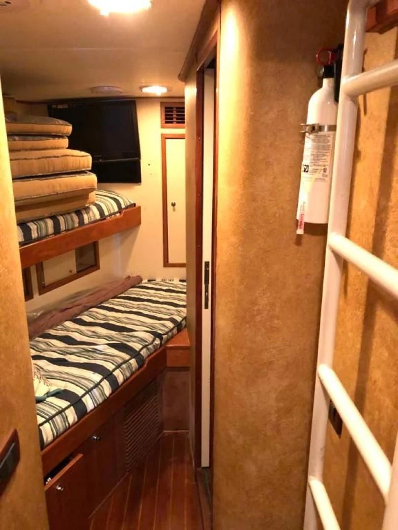 a room with a bed and a desk aboard PRIME TIME Yacht for Sale