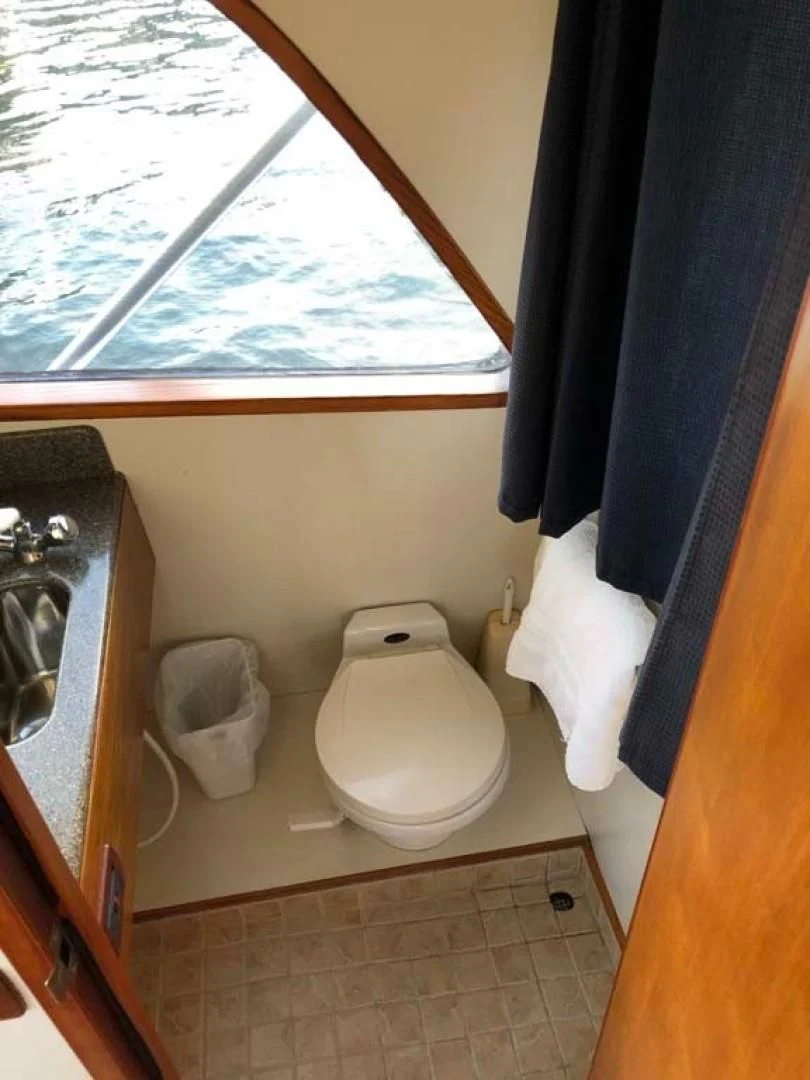 a bathroom with a toilet and a window aboard PRIME TIME Yacht for Sale