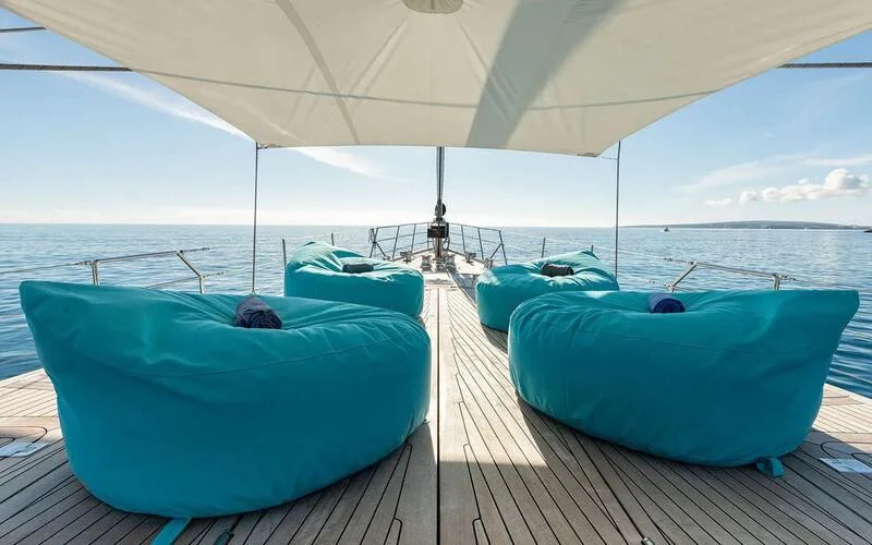 a couple of blue lounge chairs on a deck with a large body of water in the background aboard SERENDIPITY I Yacht for Charter