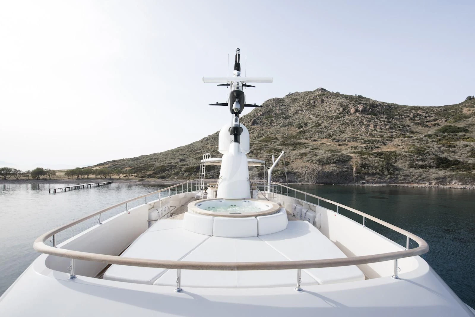 a white boat on a body of water with hills in the background aboard THERAPY Yacht for Sale