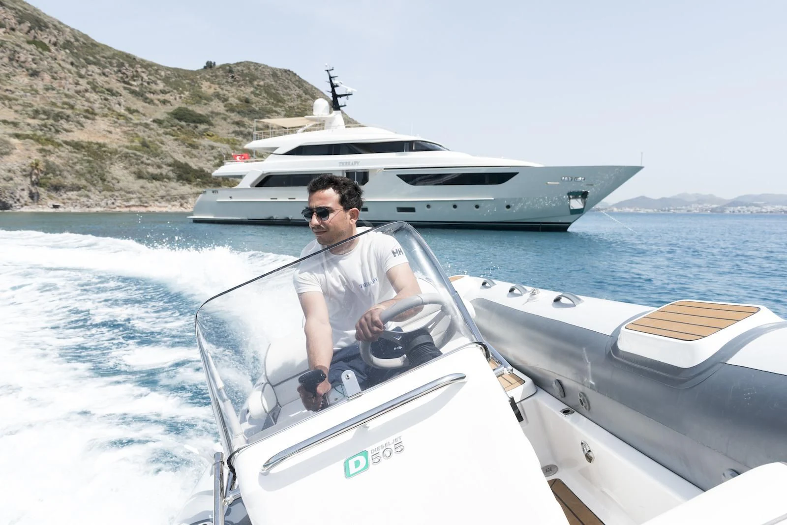 a man on a boat with a large ship in the background aboard THERAPY Yacht for Sale