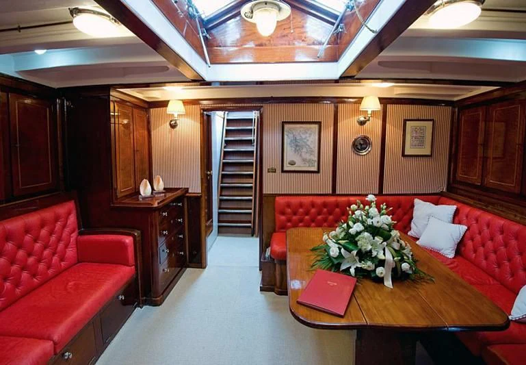 a living room with a staircase and red couches aboard ORIANDA Yacht for Charter