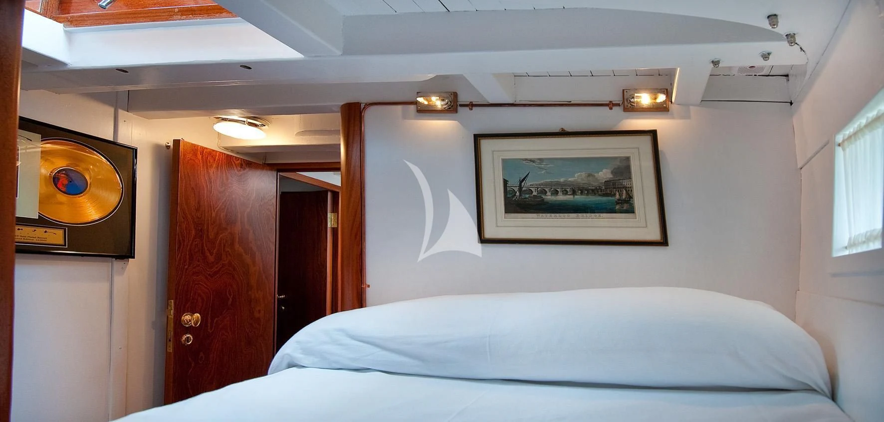 a bed with a white sheet and a television on the wall aboard ORIANDA Yacht for Charter