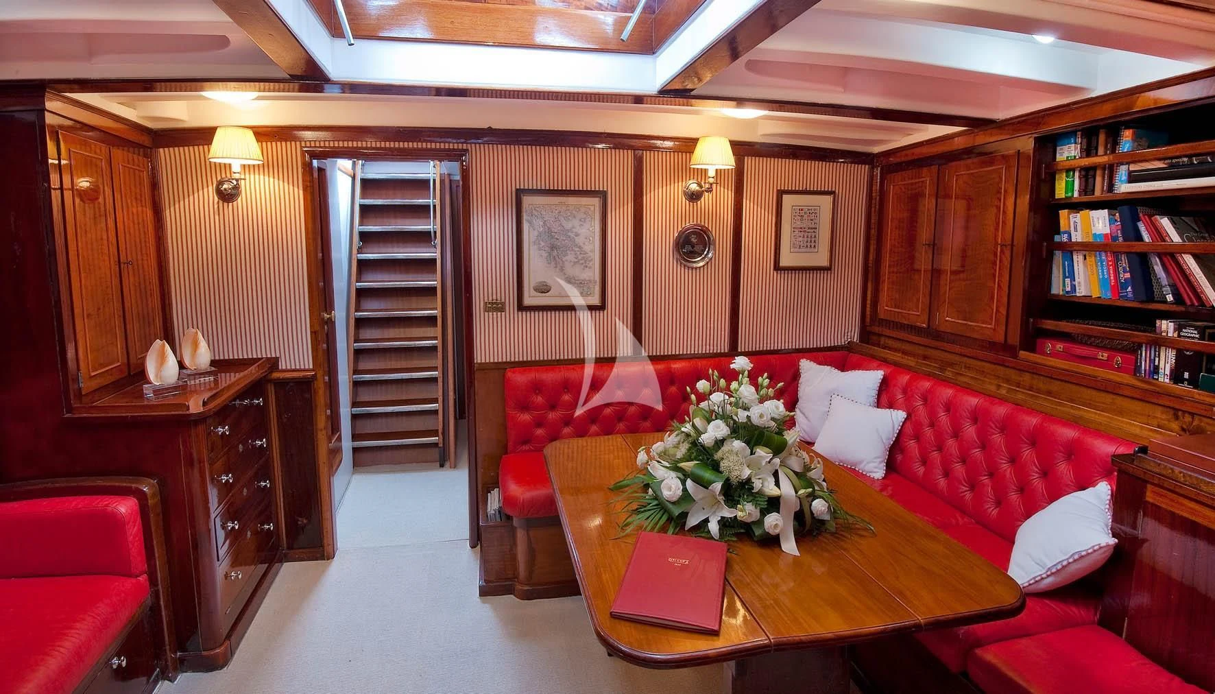 a living room with a red couch and a table aboard ORIANDA Yacht for Charter