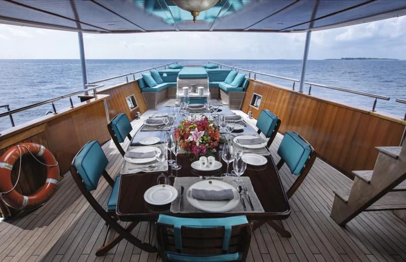 a table set for a meal on a deck overlooking the ocean aboard KALIZMA Yacht for Sale