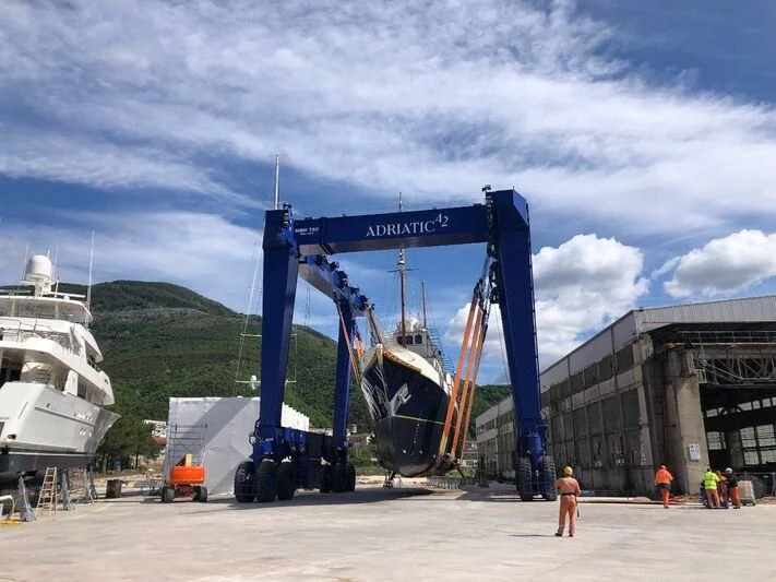 a large blue crane next to a boat and a building aboard KALIZMA Yacht for Sale