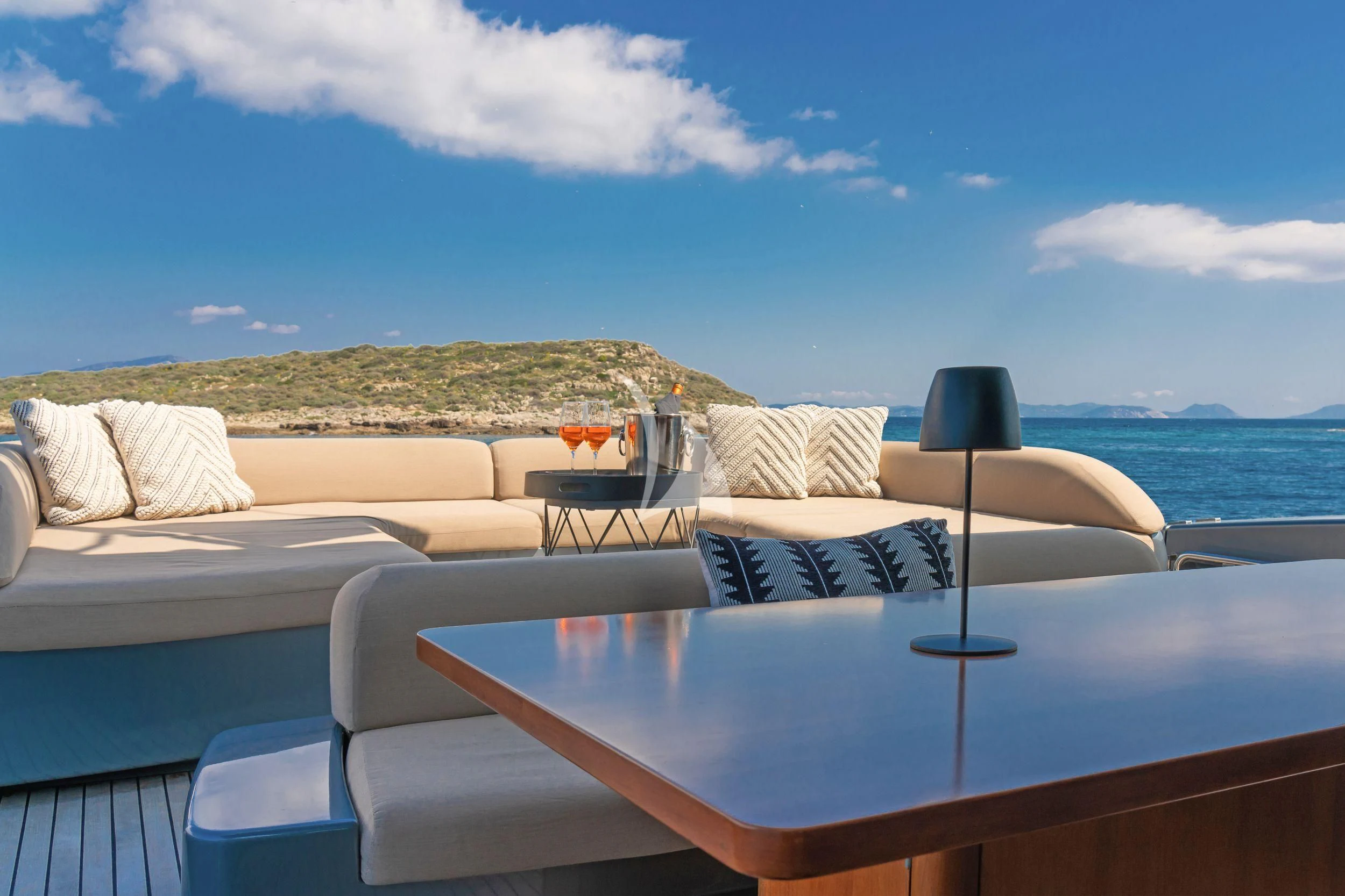 a table and a couch on a balcony overlooking a body of water aboard WHATEVER Yacht for Charter