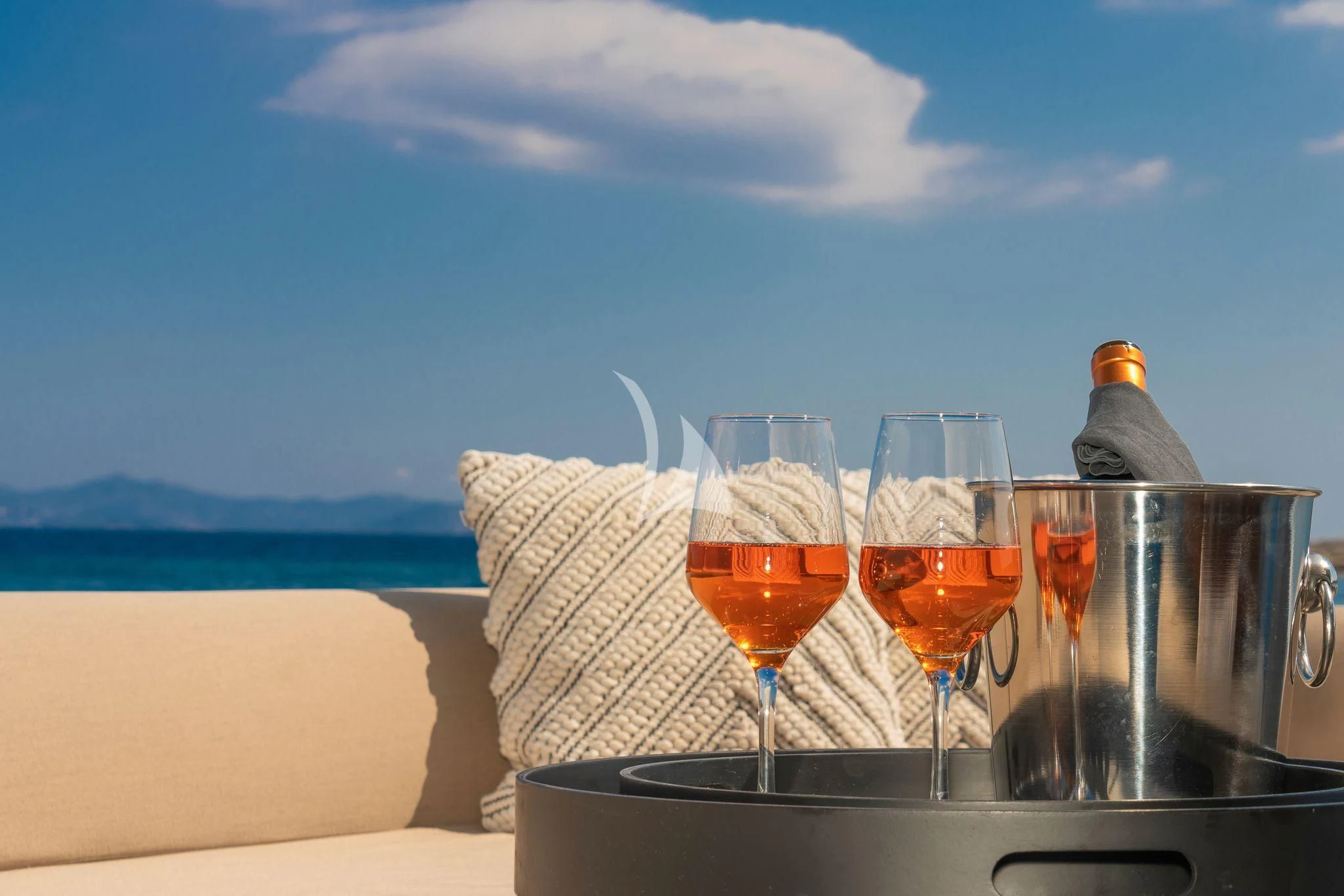 a group of glasses with drinks on a table with a view of the ocean and mountains in the aboard WHATEVER Yacht for Charter