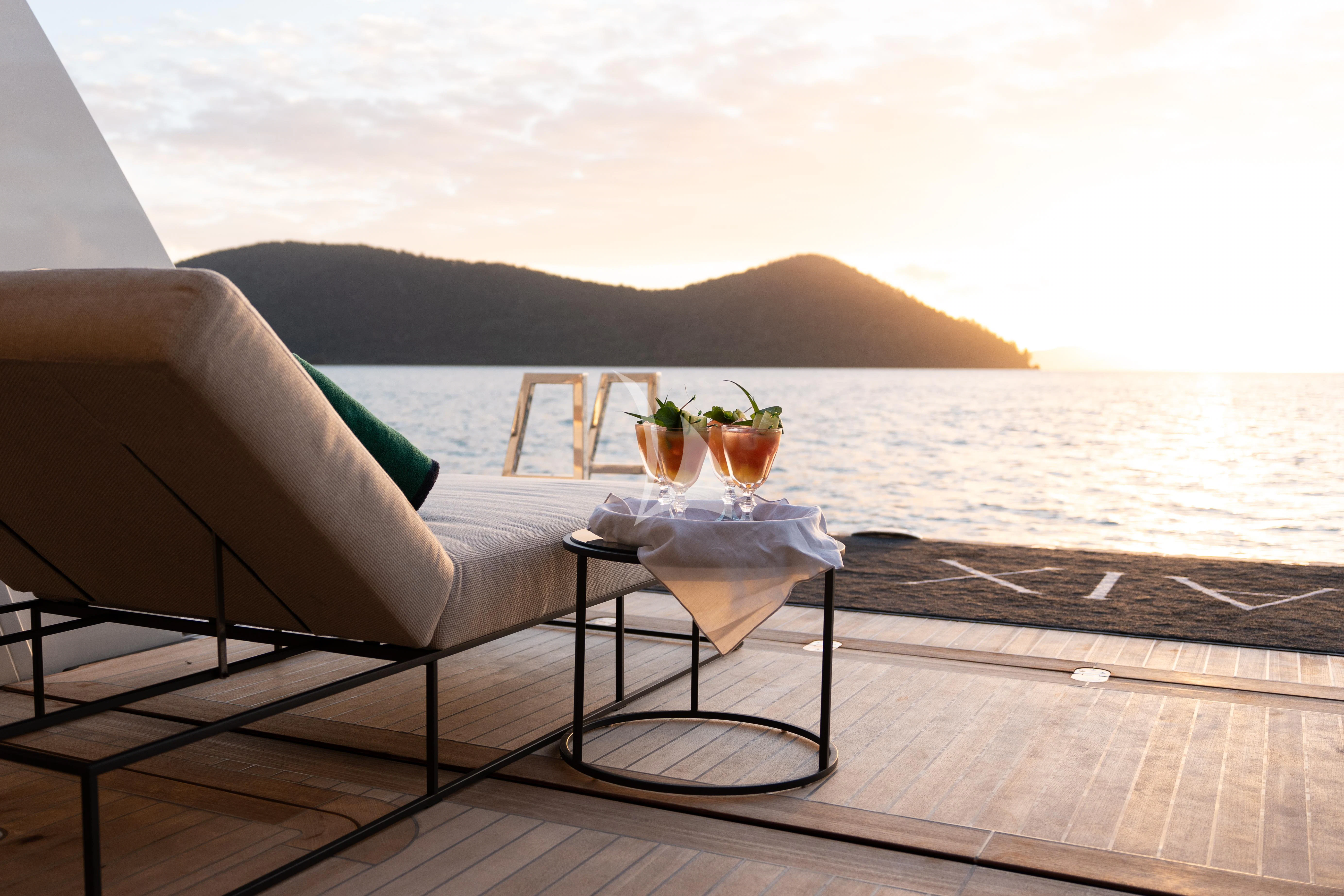 a white couch on a deck overlooking a body of water aboard AIX Yacht for Sale