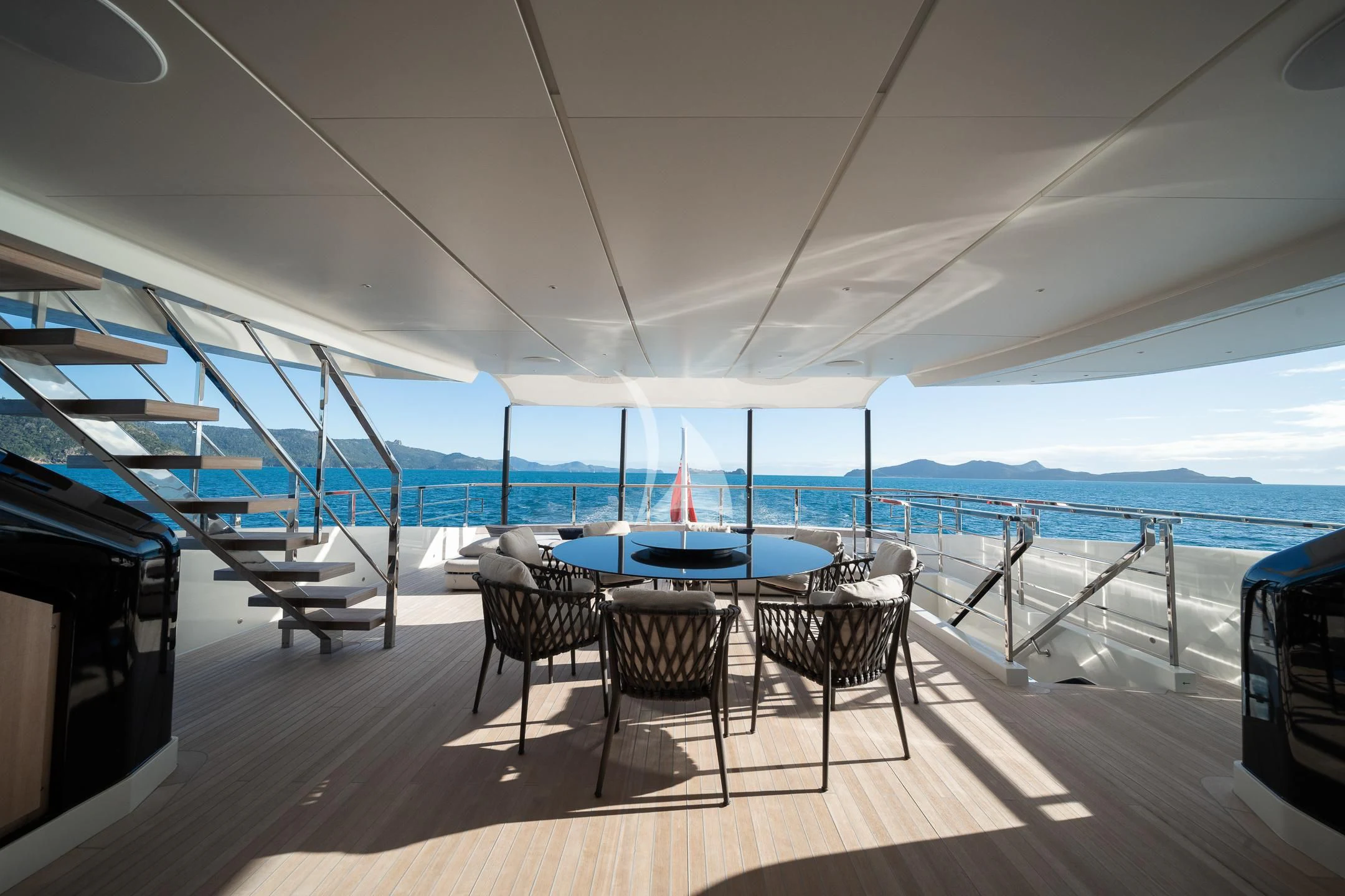a table and chairs on a deck overlooking a body of water aboard AIX Yacht for Sale