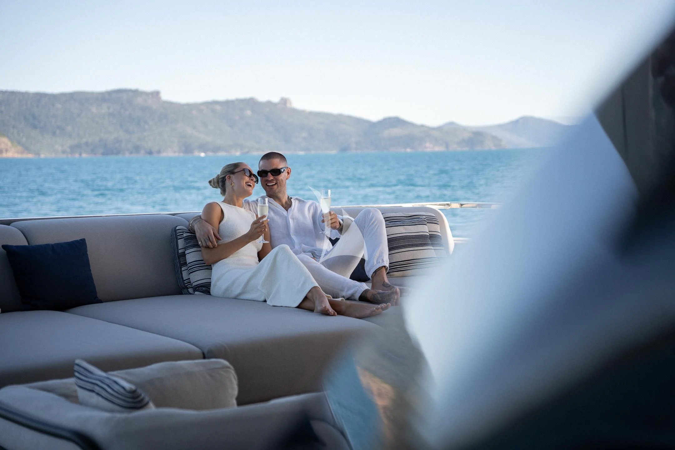 a man and woman sitting on a boat with drinks aboard AIX Yacht for Sale