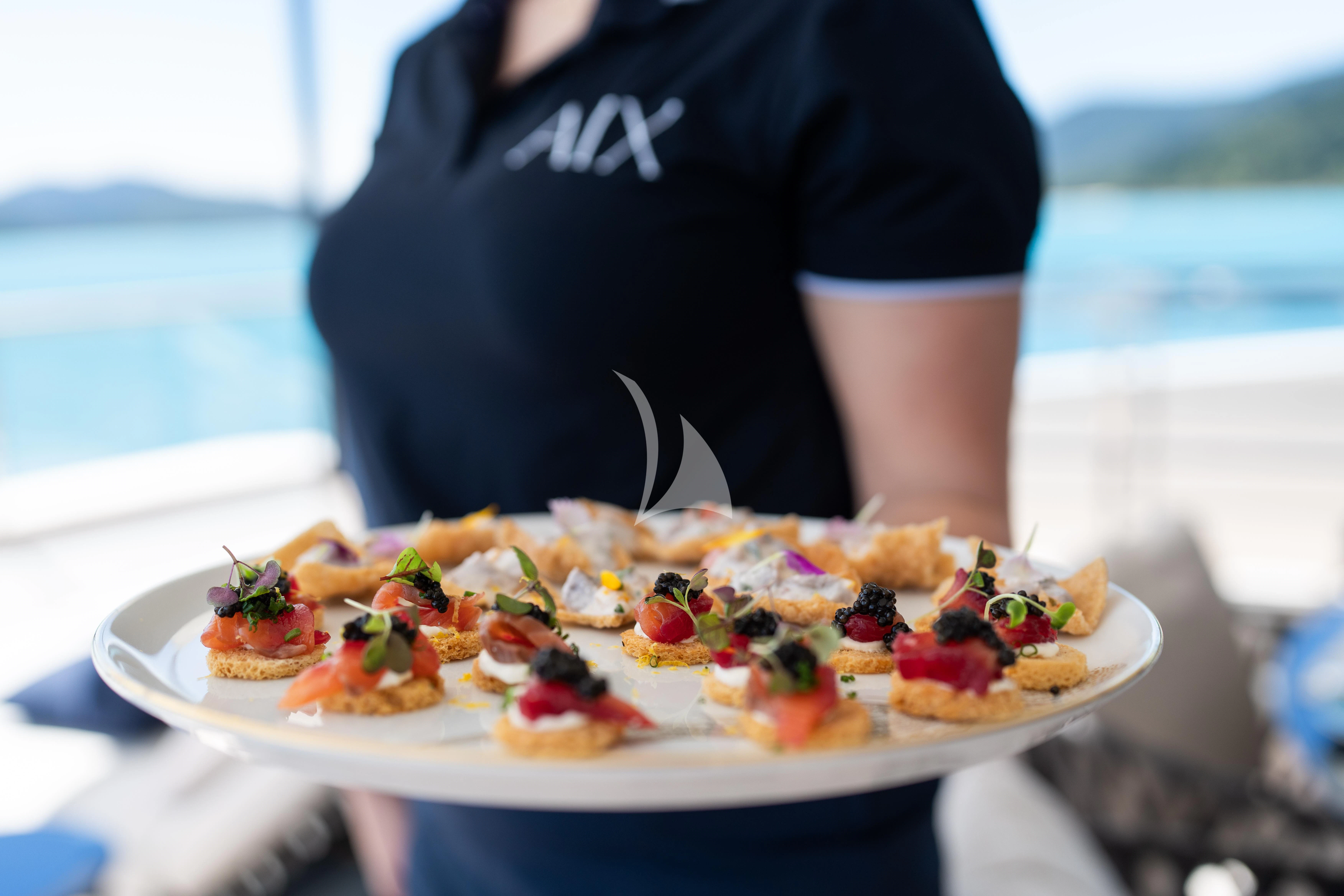 a person holding a plate of food aboard AIX Yacht for Sale