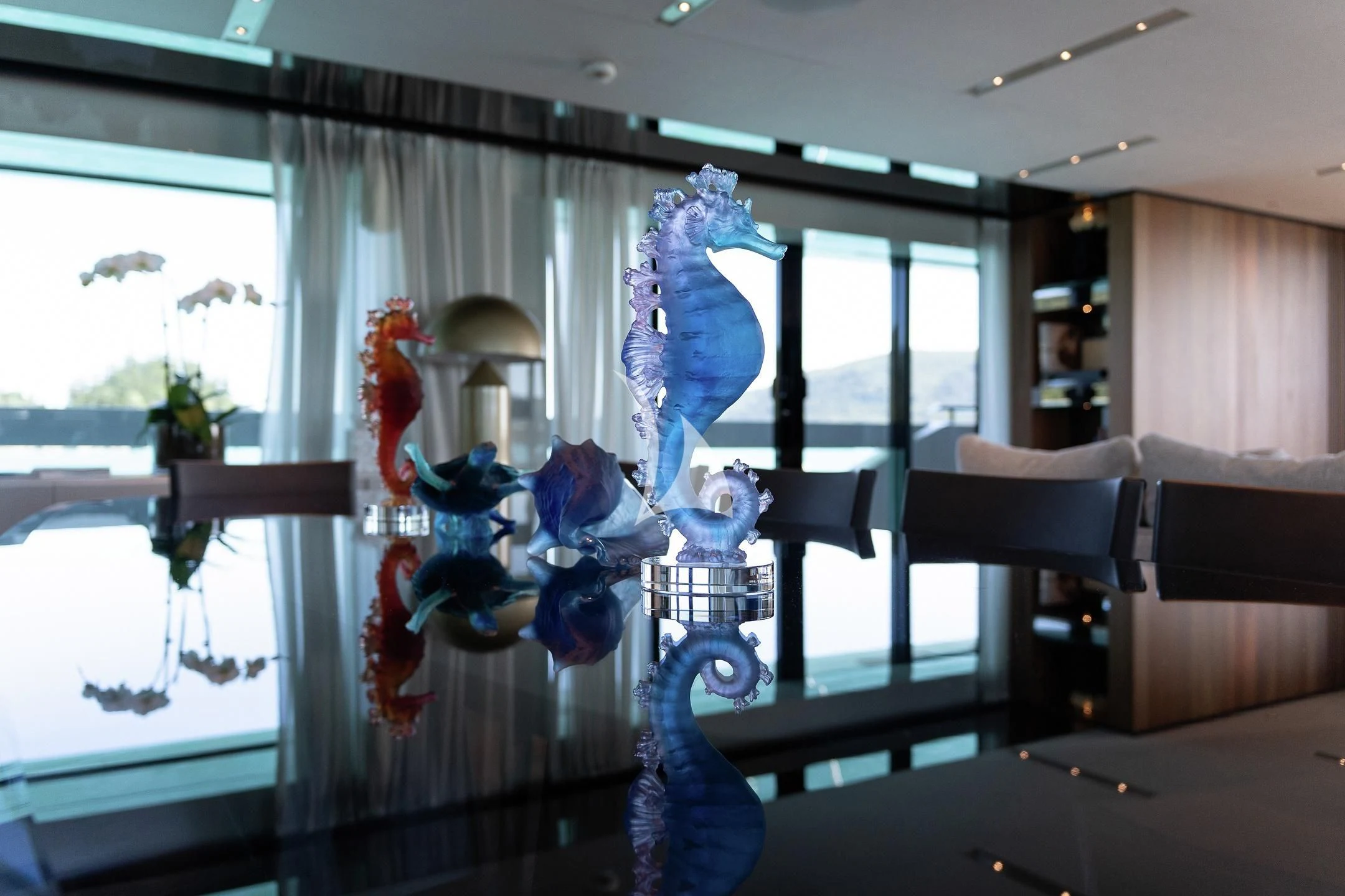 a room with a glass wall and a chandelier aboard AIX Yacht for Sale