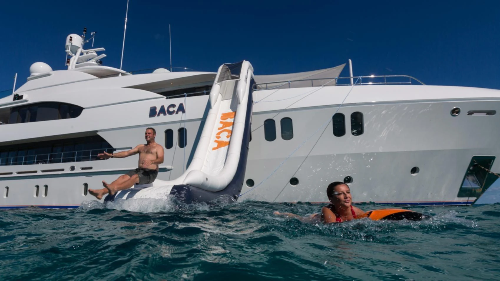 a man and woman in the water next to a boat aboard BACA Yacht for Charter