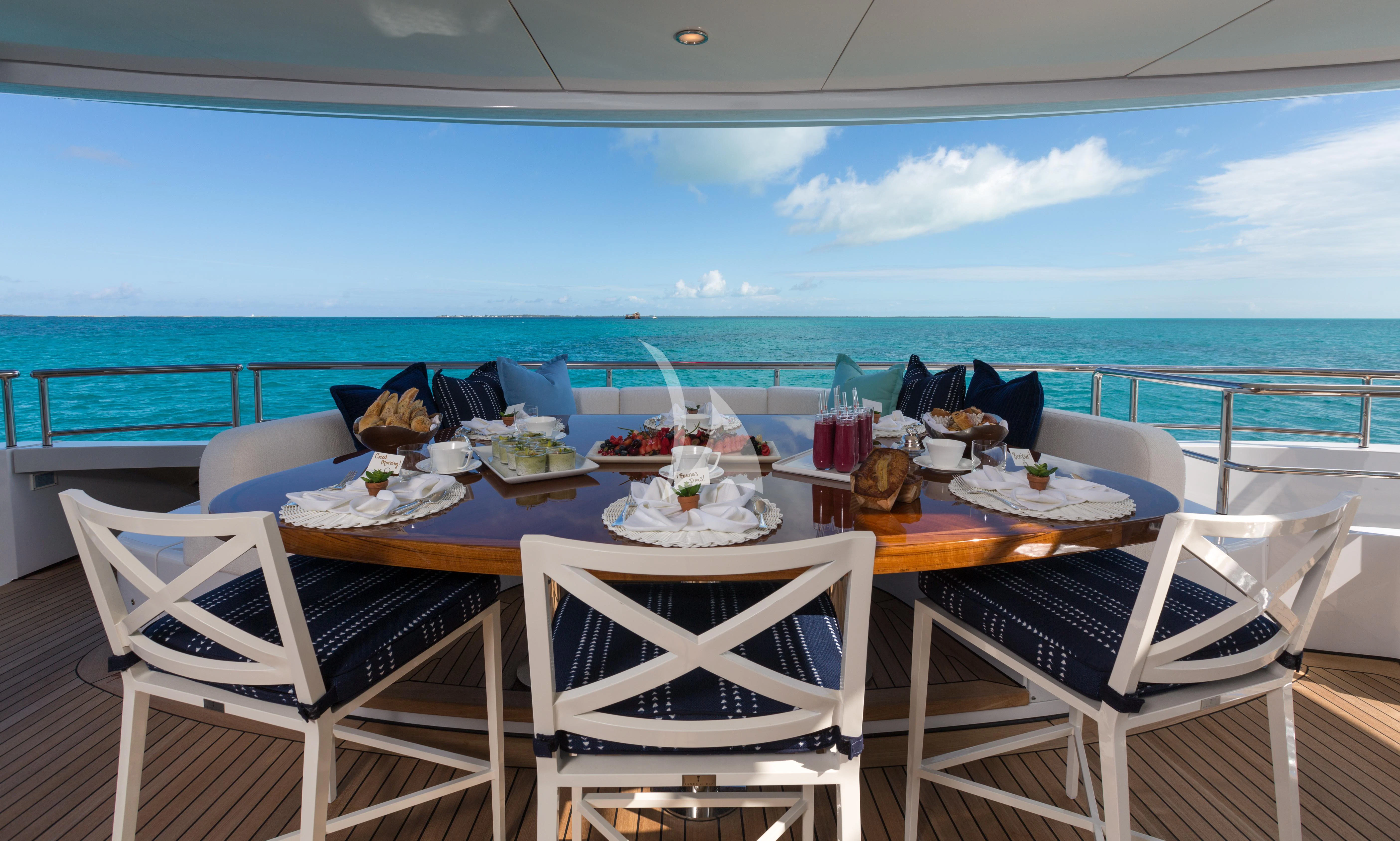 a table with chairs and a pool aboard BACA Yacht for Charter