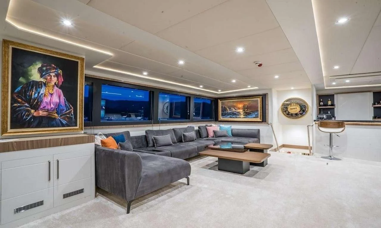 a living room with a large gray couch and a large tv aboard DEEP WATER Yacht for Charter