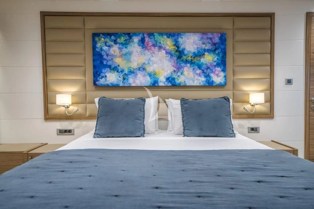 a bed with a painting on the wall aboard DEEP WATER Yacht for Charter