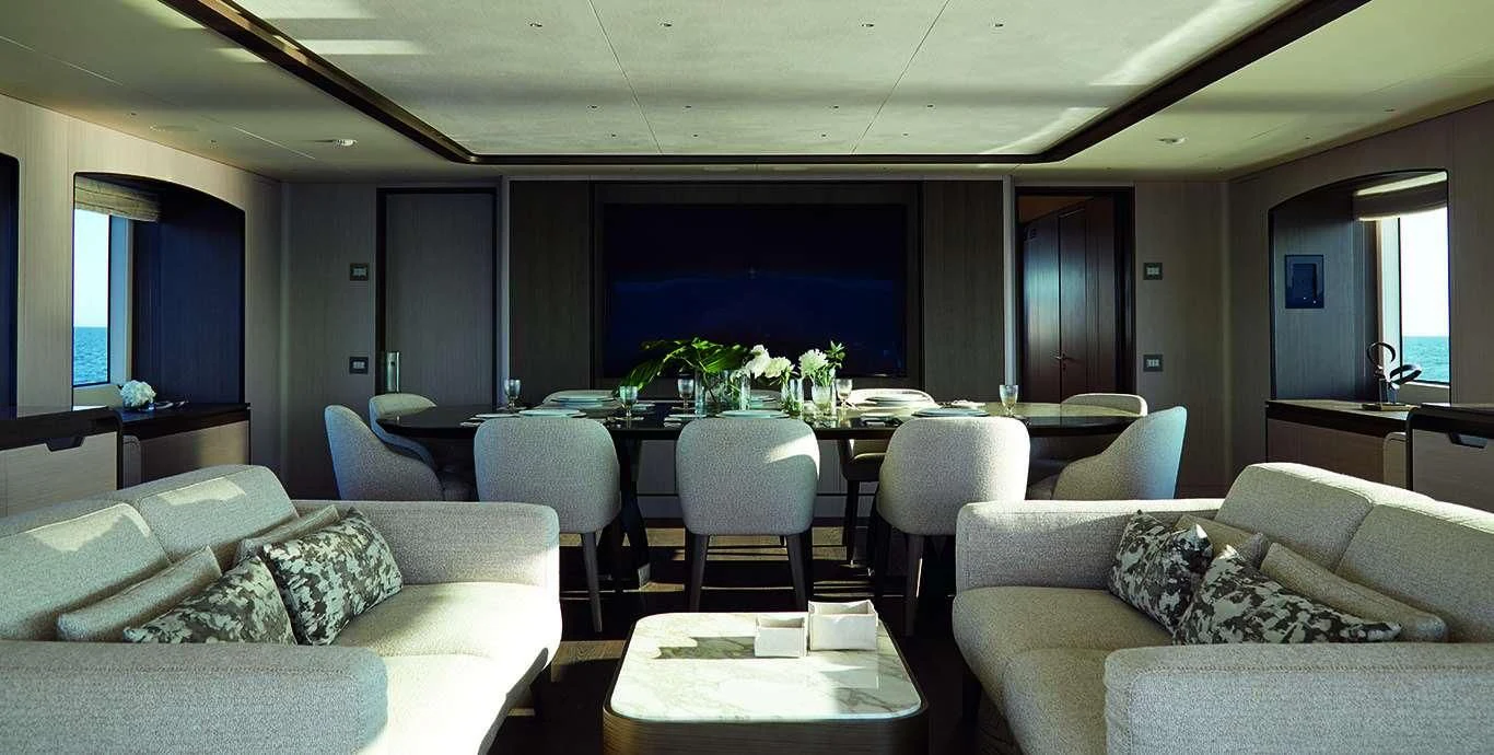 a living room with a table and couches aboard CASA Yacht for Sale