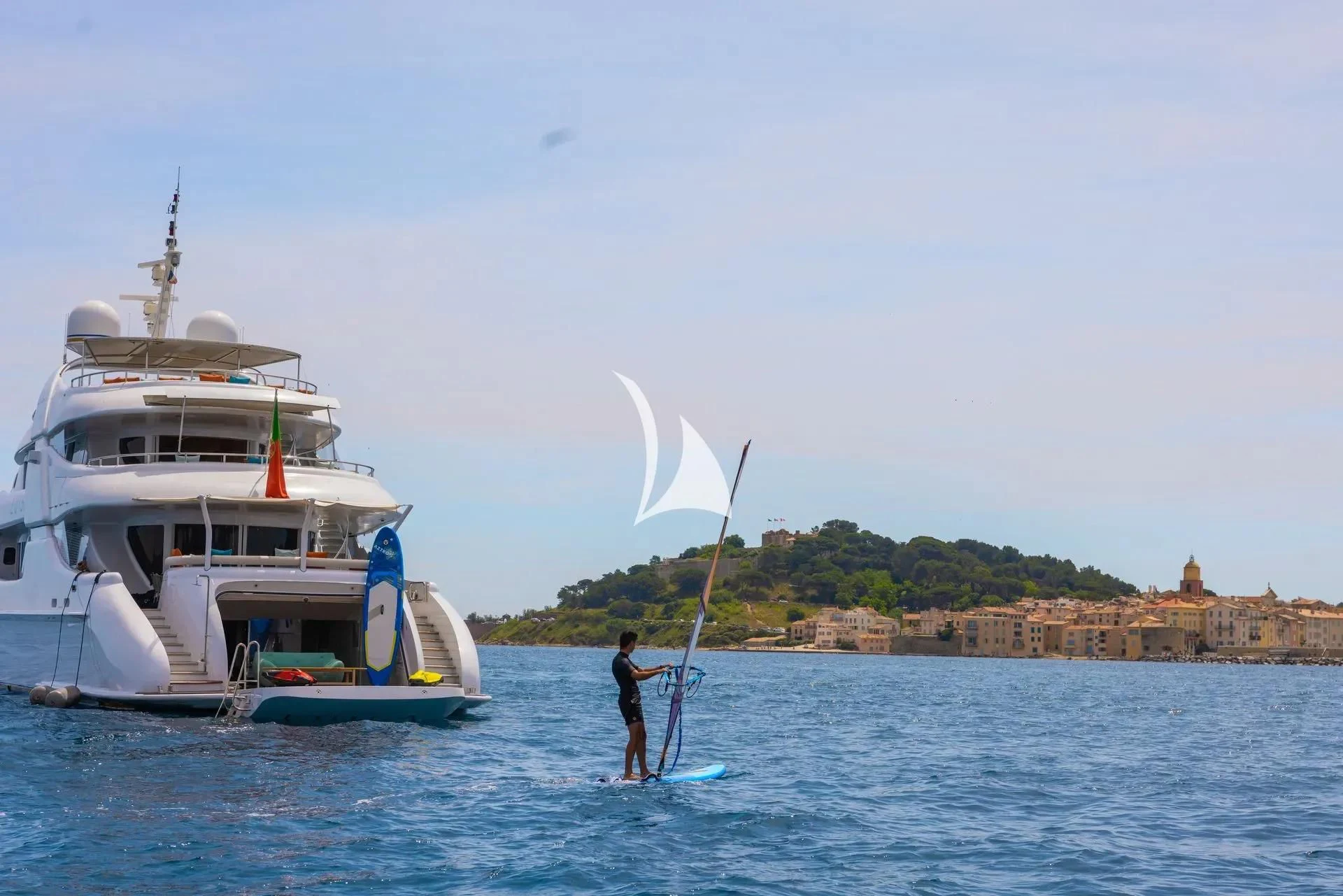 a person on a surfboard next to a boat in the water aboard LUISA Yacht for Charter