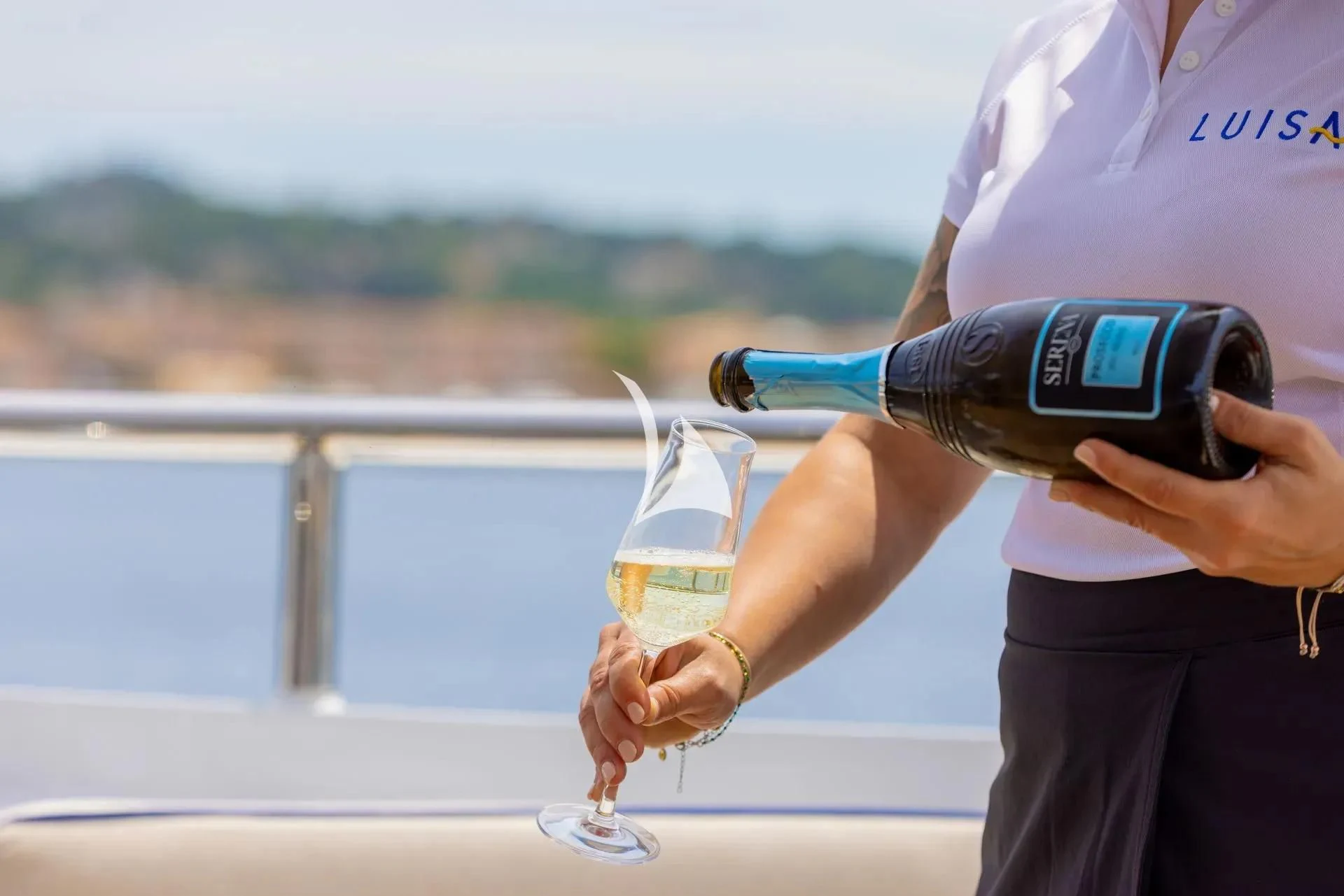 a person pouring a bottle of wine aboard LUISA Yacht for Charter