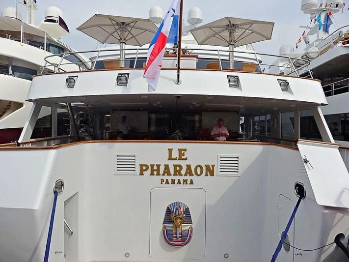 a white yacht with a flag on the front aboard LE PHARAON Yacht for Sale