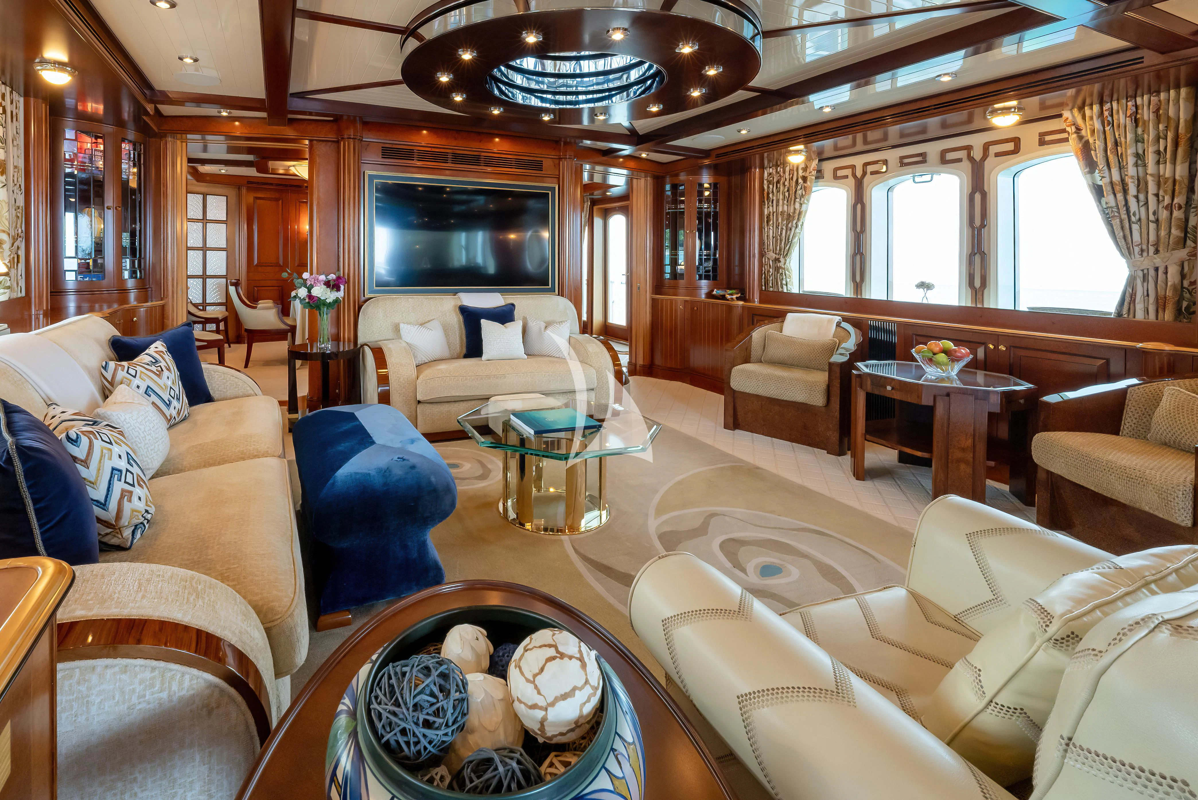 a living room with a large blue chair and a round table aboard NADAN Yacht for Sale