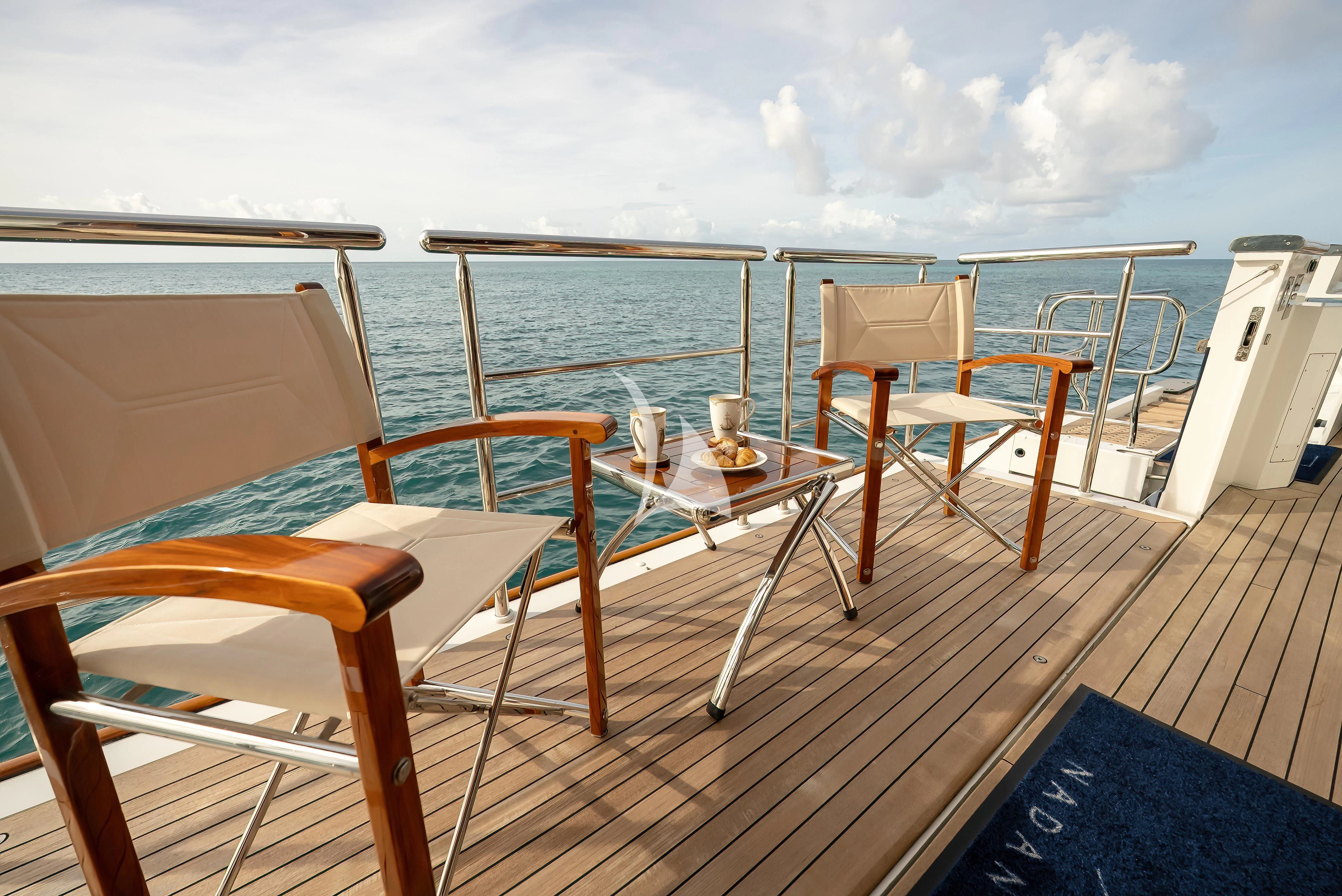 a deck with chairs and a table on it aboard NADAN Yacht for Sale