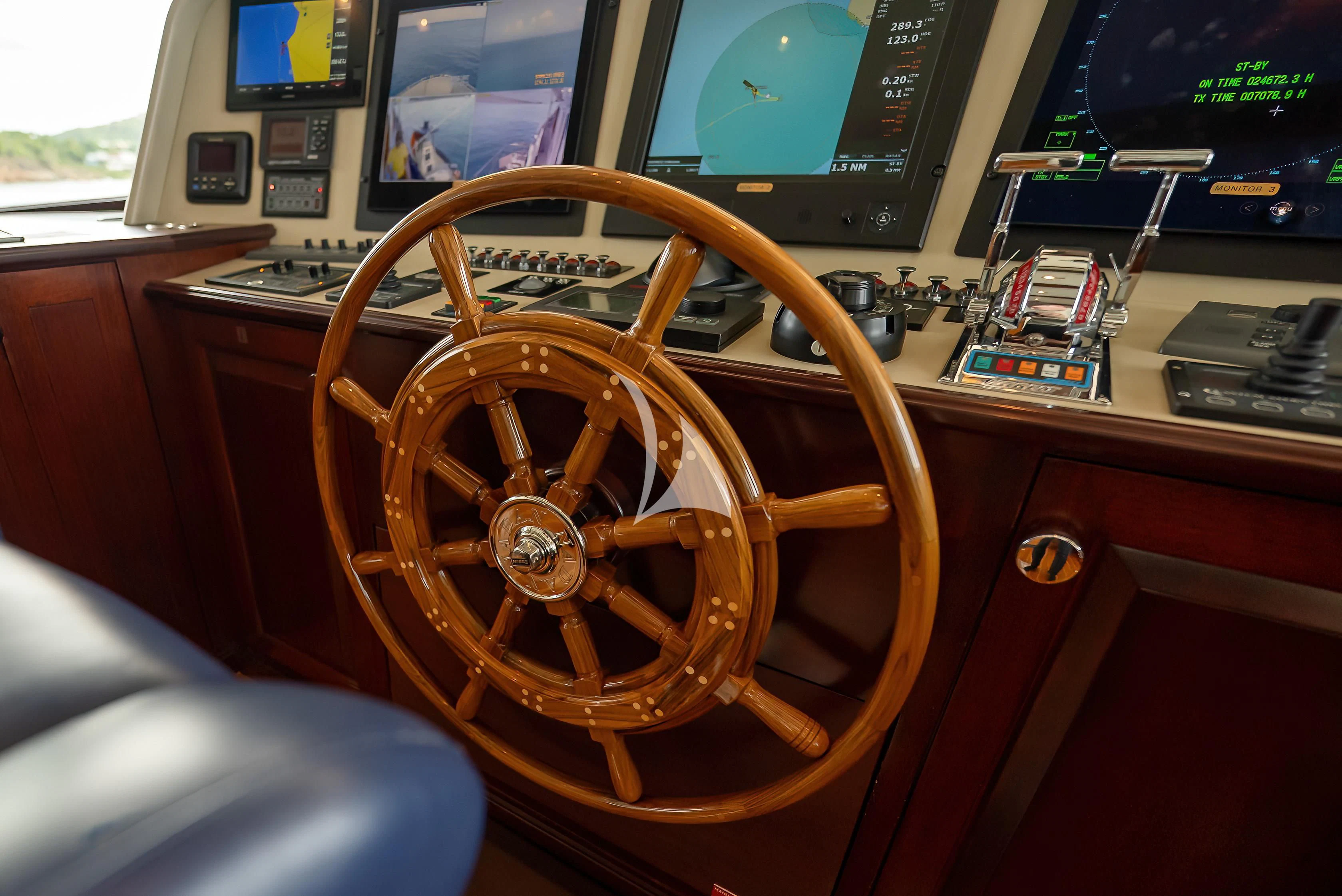 a wooden steering wheel on a wooden table in a room with a television and other electronic devices aboard NADAN Yacht for Sale