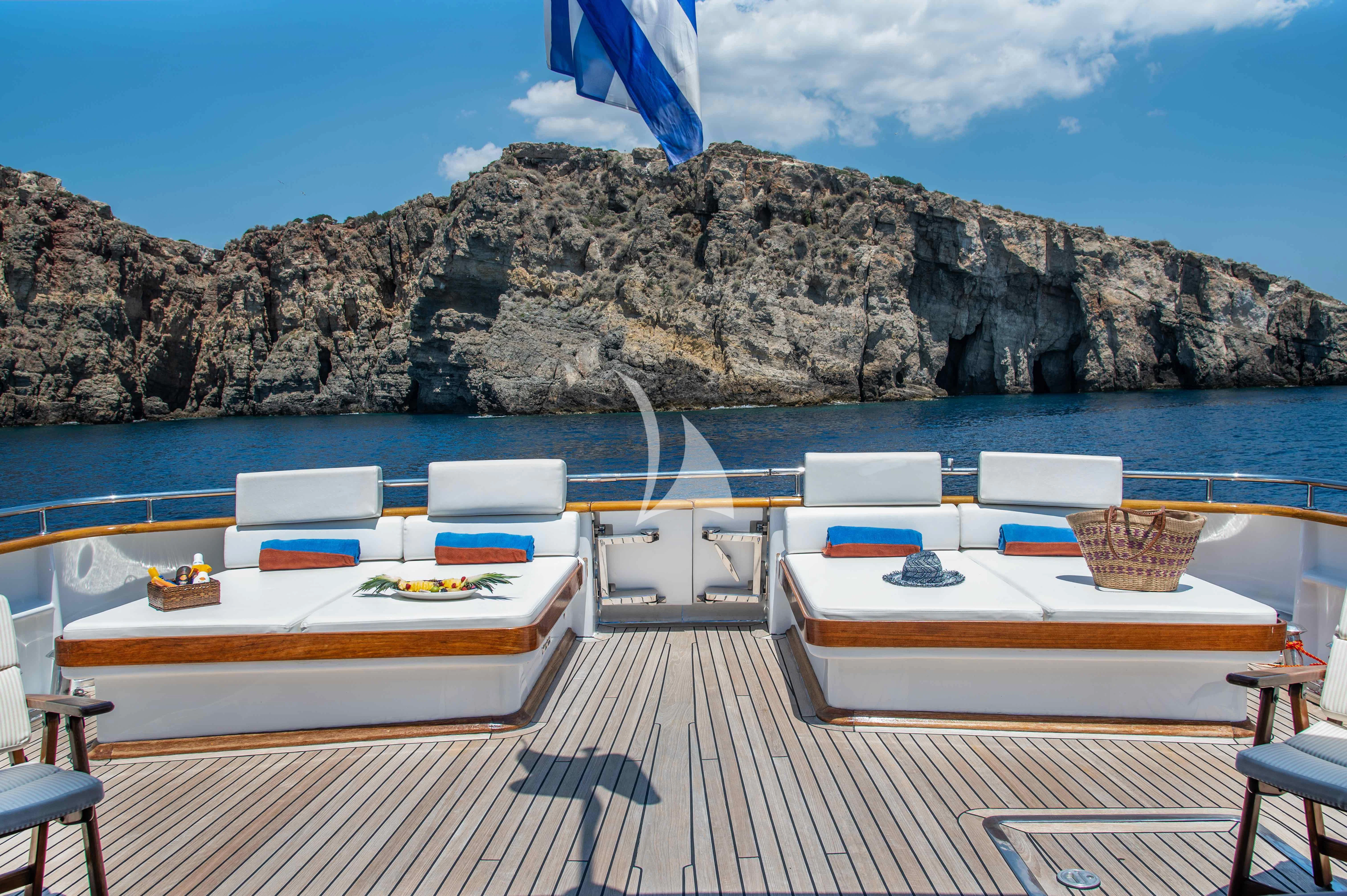 a deck with chairs and tables on it by a body of water aboard OKTANA Yacht for Sale
