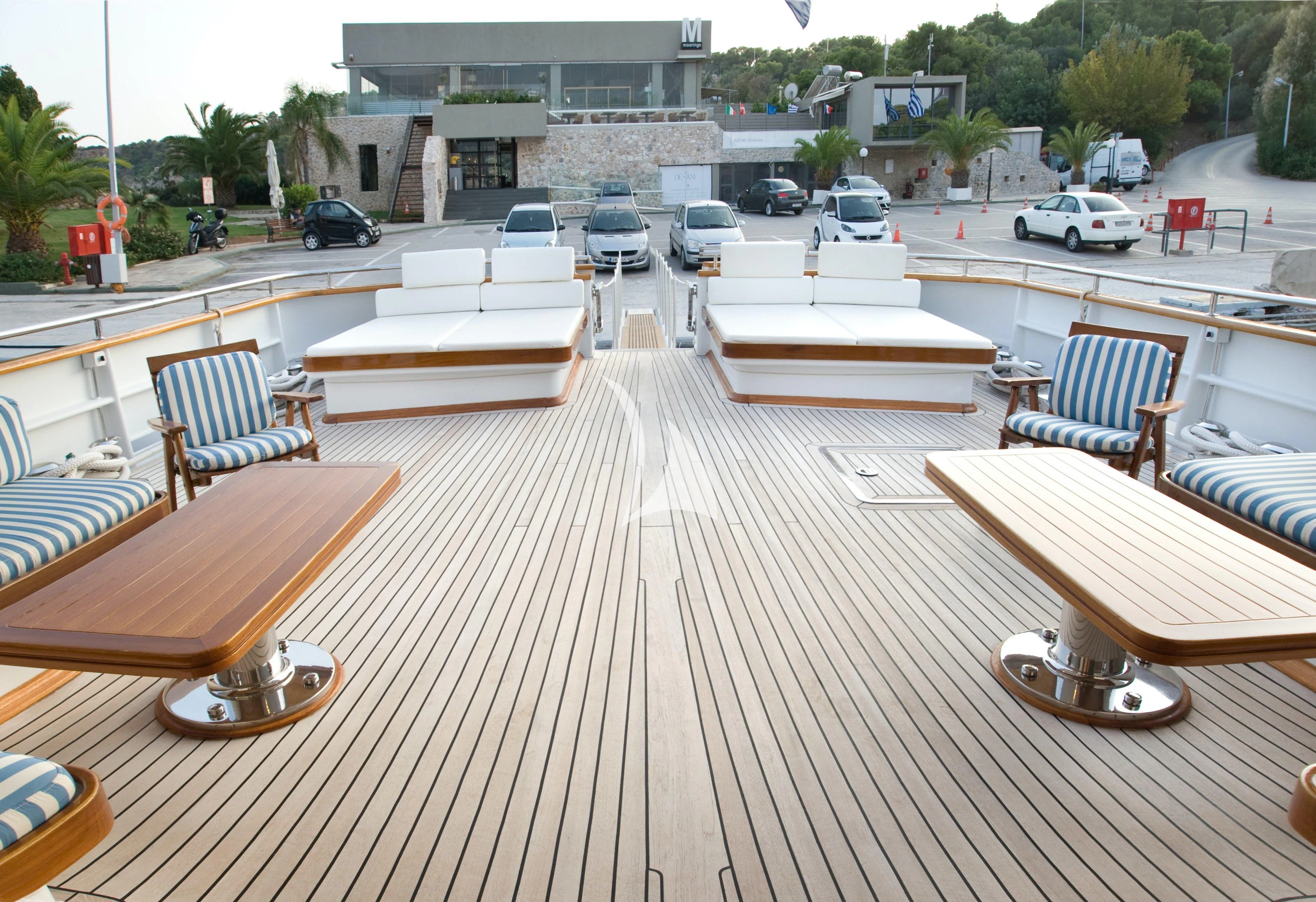 a deck with a few chairs and a table with a bench on it aboard OKTANA Yacht for Sale
