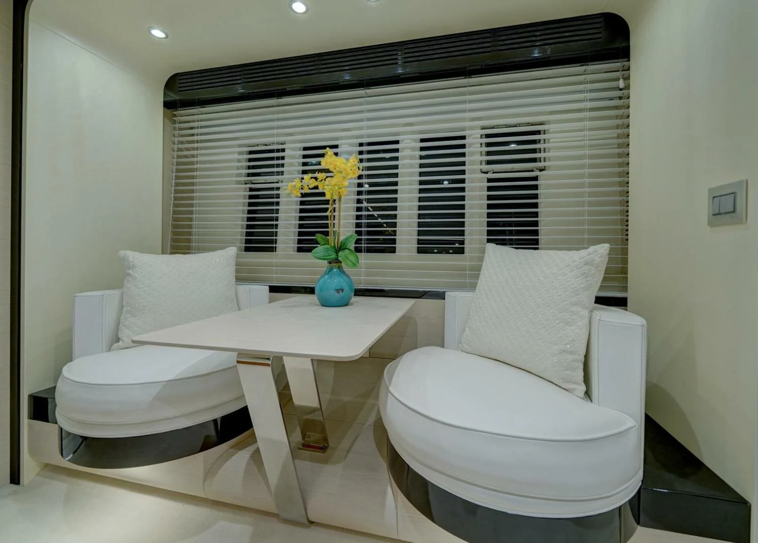 a white chair next to a white table with yellow flowers in a room with a black wall and aboard 80 AZIMUT Yacht for Sale