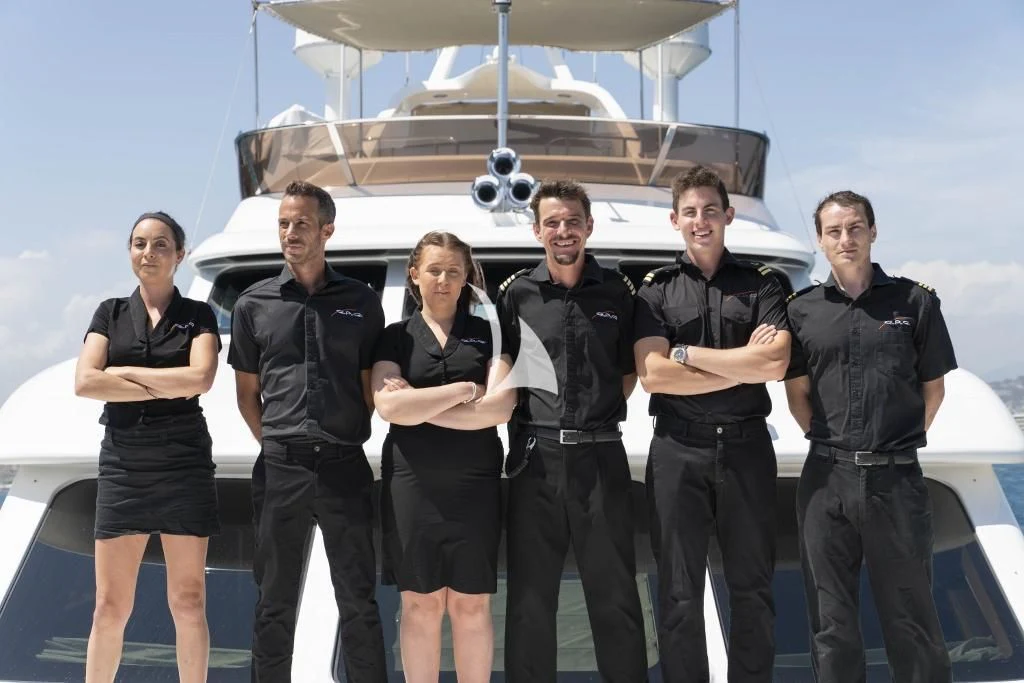a group of people posing for a photo in front of a helicopter aboard QUID PRO QUO Yacht for Sale