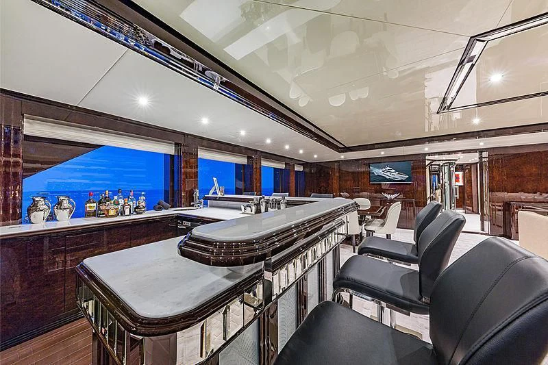 a room with a bar and chairs aboard SPECTRE Yacht for Sale